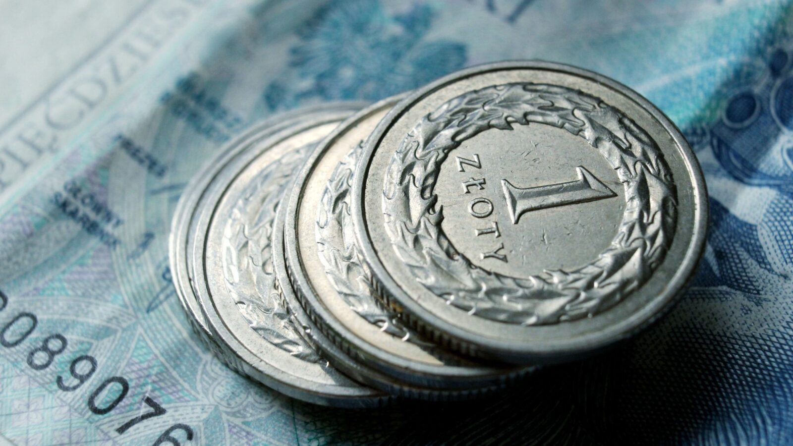 Monety jednozłotowe leżące na banknocie 50 zł – raty kredytu frankowego spłacane w złotych